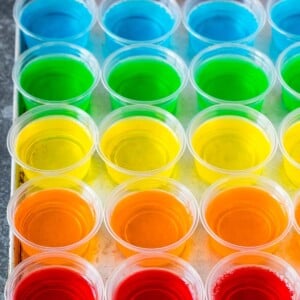 Rows of rainbow colored Jello shots lined up on a sheet pan.