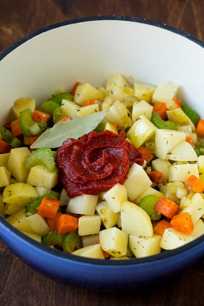 Potatoes, vegetables, herbs and tomato paste in a soup pot.