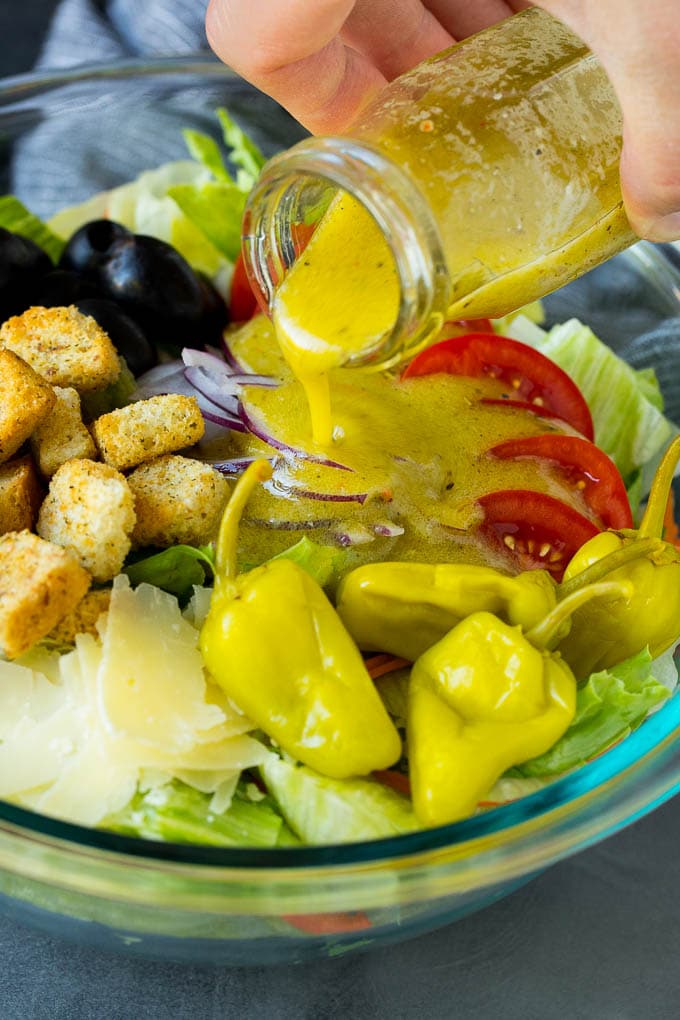 Dressing being poured over a bowl of salad.