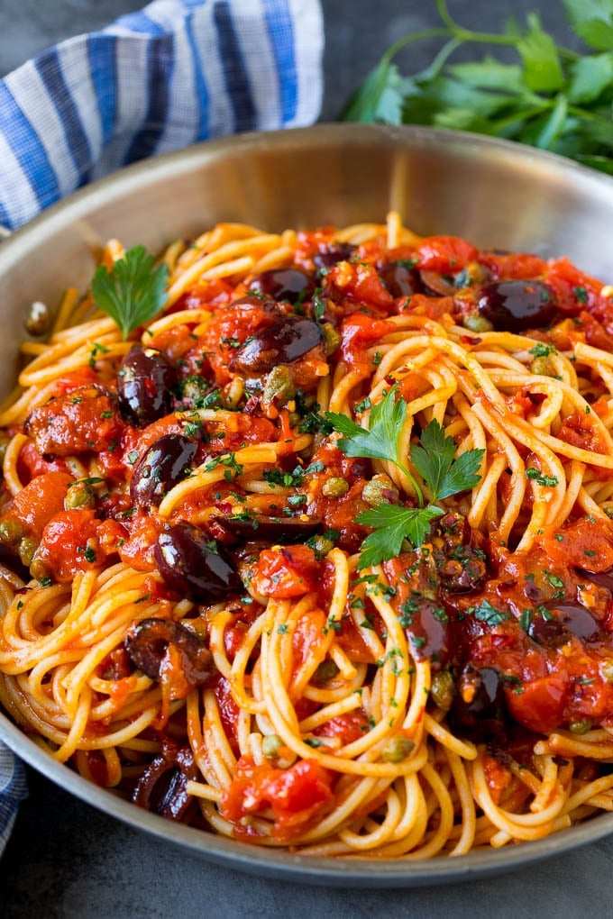 Pasta puttanesca with olives and capers in tomato sauce.
