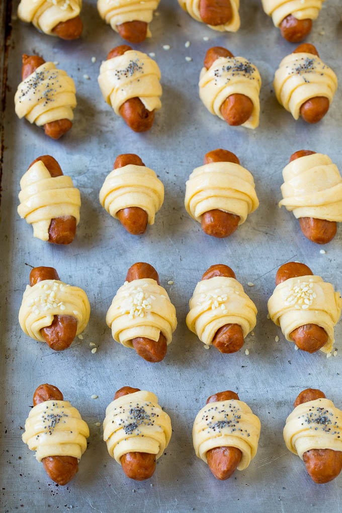 Mini hot dogs wrapped in crescent dough and topped with seeds.