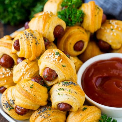 A plate of pigs in a blanket served with ketchup.