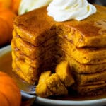 A stack of pumpkin pancakes with a fork holding cut pieces of pancake.
