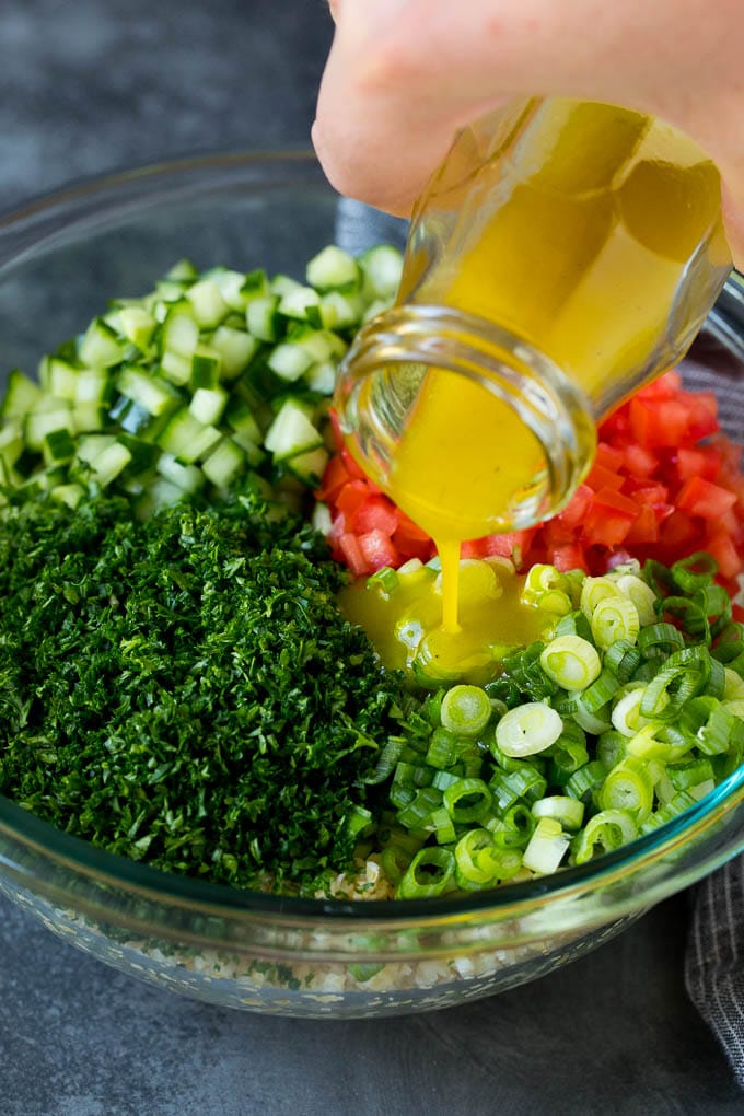 Dressing being poured into a bowl of bulgur wheat salad.