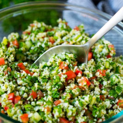 A bowl of tabbouleh with a serving spoon in it.