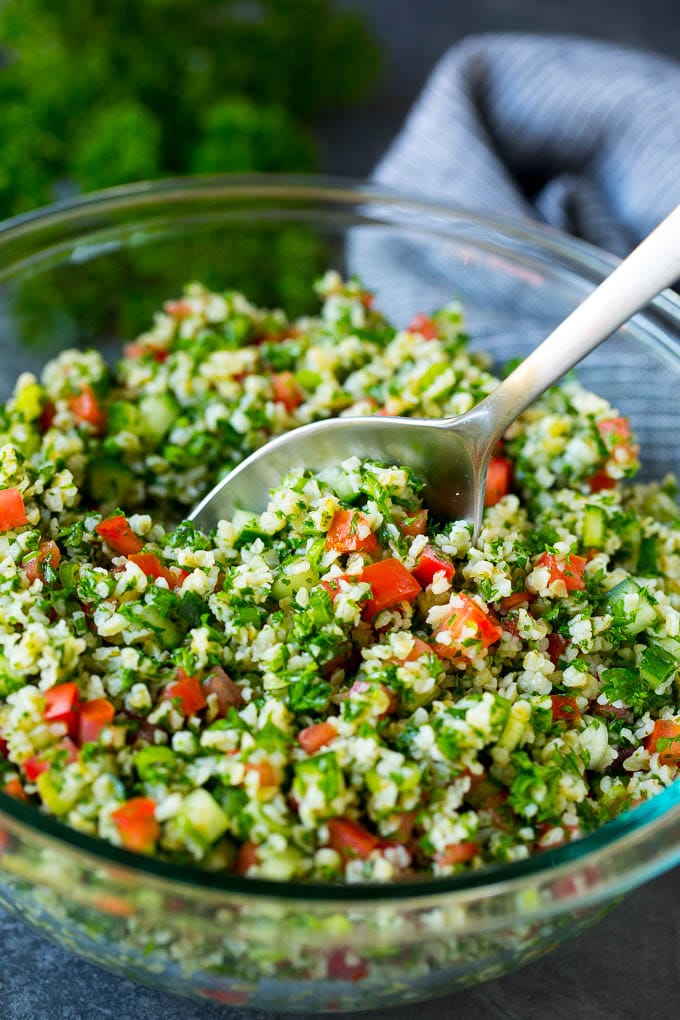 A bowl of tabbouleh with a serving spoon in it.