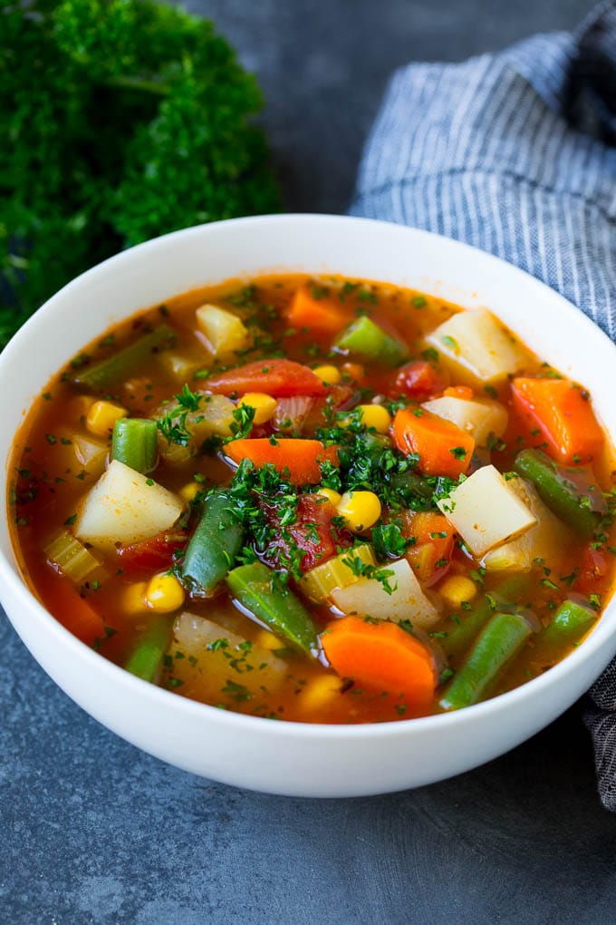 A bowl of vegetable soup with green beans, potatoes, carrots and corn.