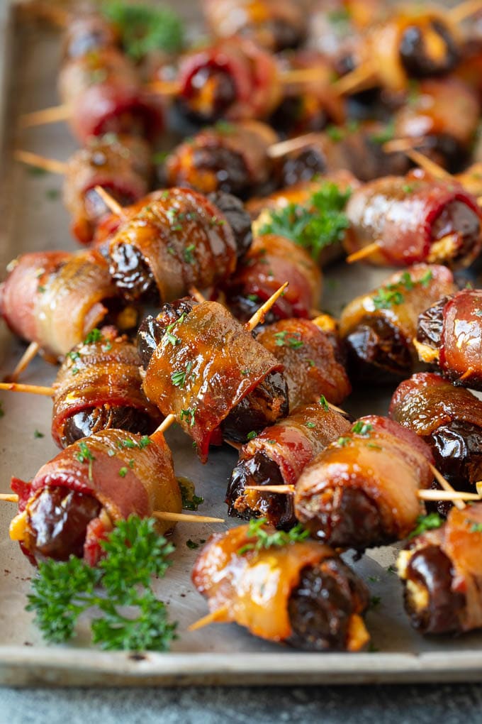 Bacon wrapped dates on a sheet pan garnished with parsley.