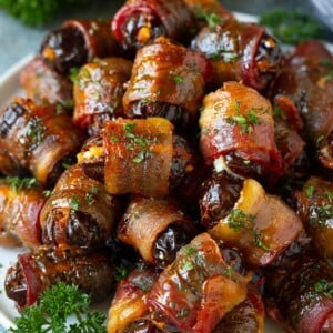 A plate of bacon wrapped dates stuffed with goat cheese.