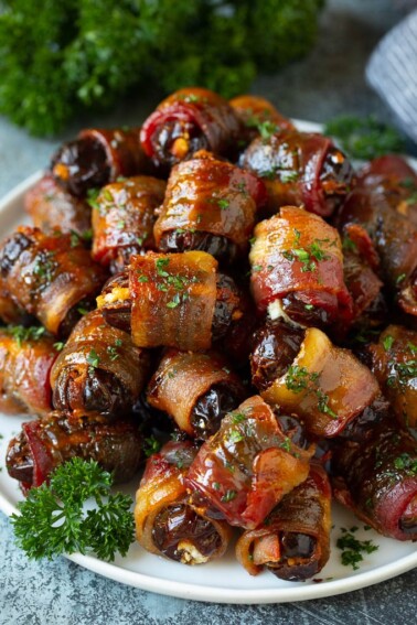 A plate of bacon wrapped dates stuffed with goat cheese.