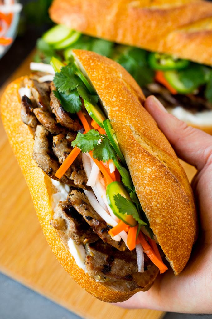 A hand holding a pork banh mi sandwich.