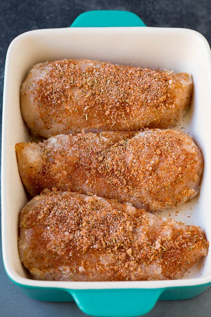 Chicken coated in seasonings in a baking dish.