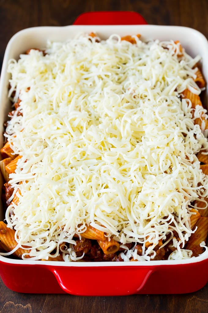 A pan of pasta in sauce topped with shredded cheese.