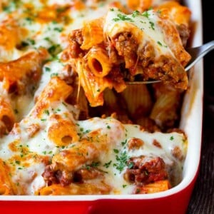 A spoon serving up a portion of baked rigatoni pasta.