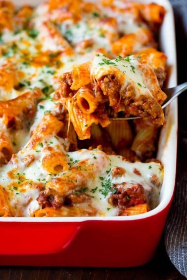 A spoon serving up a portion of baked rigatoni pasta.