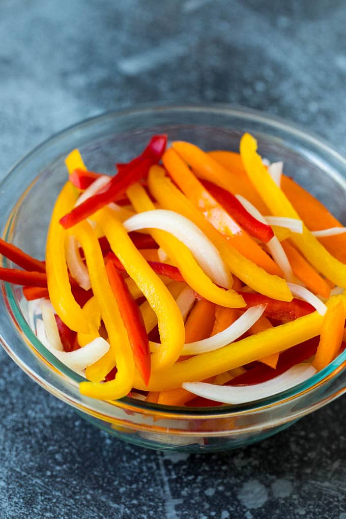 Sliced bell peppers and onions in a bowl.