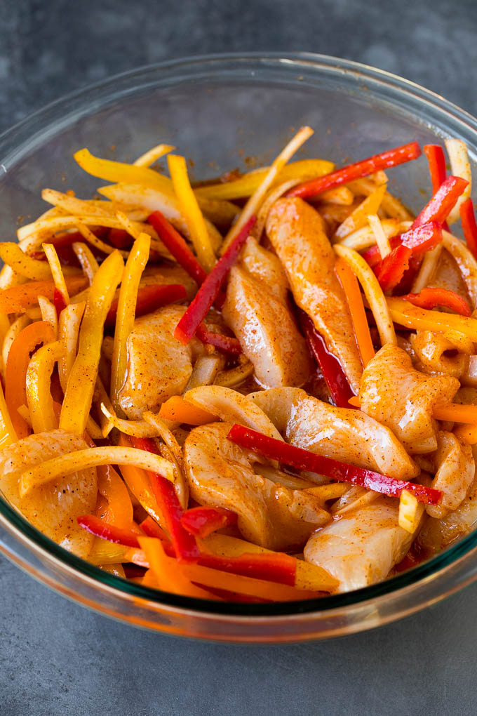 Sliced chicken, peppers and onions coated in marinade.