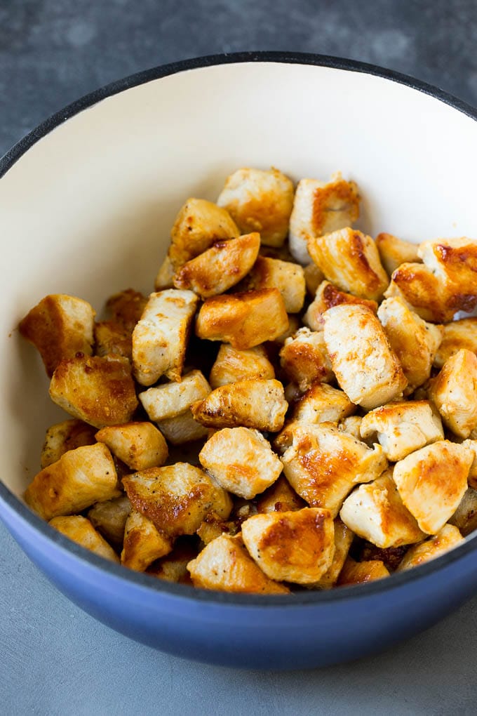 Sauteed chicken pieces in a soup pot.