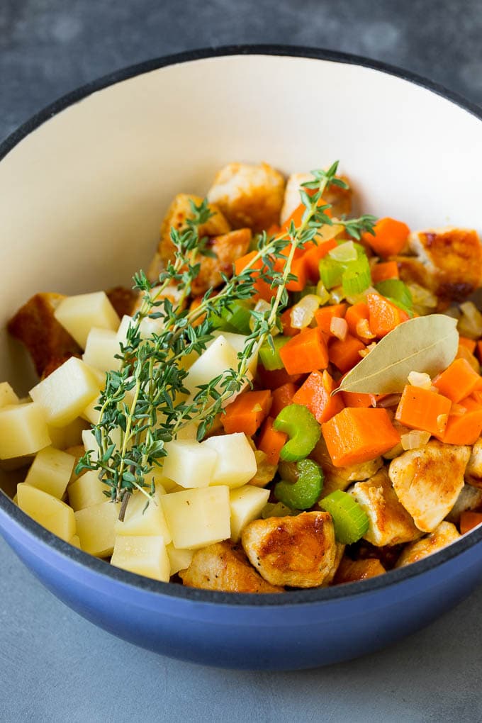 Chicken, vegetables, potatoes and herbs in a pot.