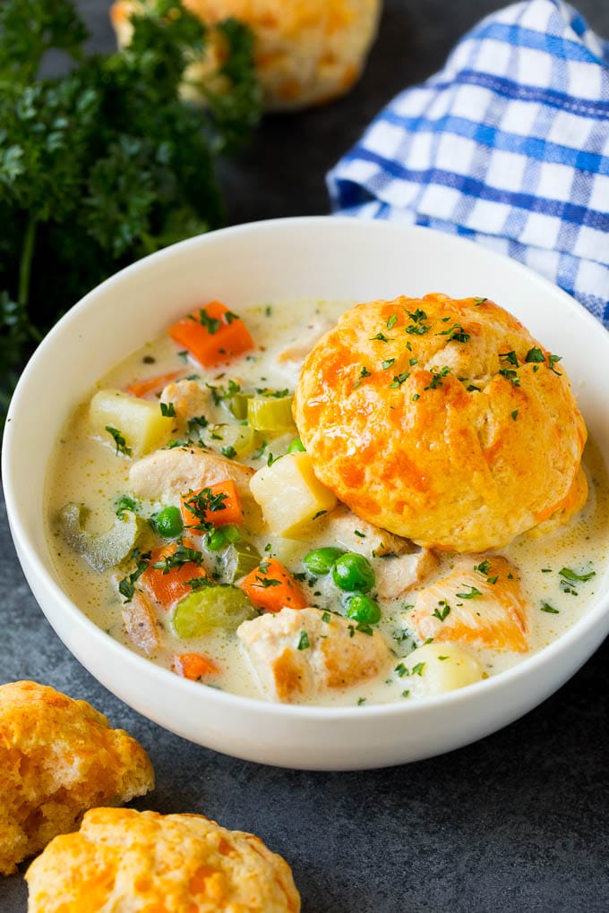 A bowl of chicken pot pie soup with a biscuit on top.