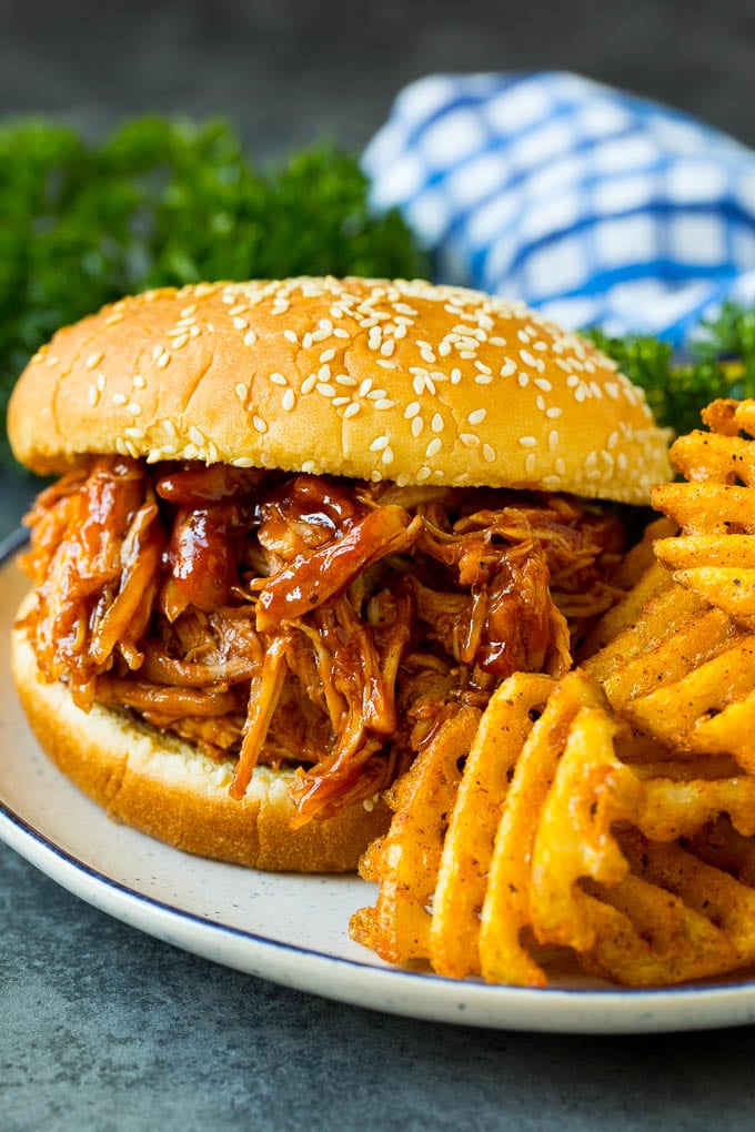 Crockpot BBQ chicken on a bun served with french fries.