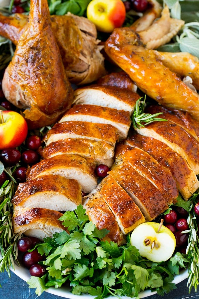 This dry brined turkey is coated in a blend of salt, herbs and spices, then roasted to golden brown perfection. Dry brined turkey sliced and served on a platter with herbs.