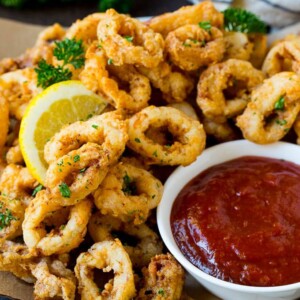 Fried calamari with lemon wedges and a side of cocktail sauce.