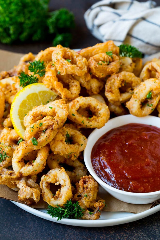 Fried calamari with lemon wedges and a side of cocktail sauce.