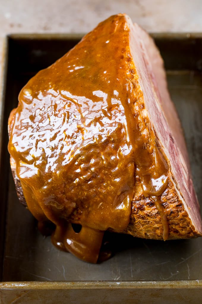 A ham coated in glaze in a baking pan.