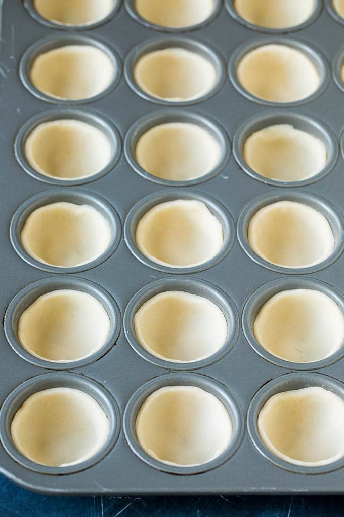 Pie crust rounds pressed into muffin tins.