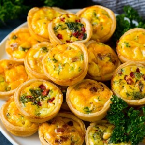 A plate of mini quiche filled with meats, vegetables and cheeses.