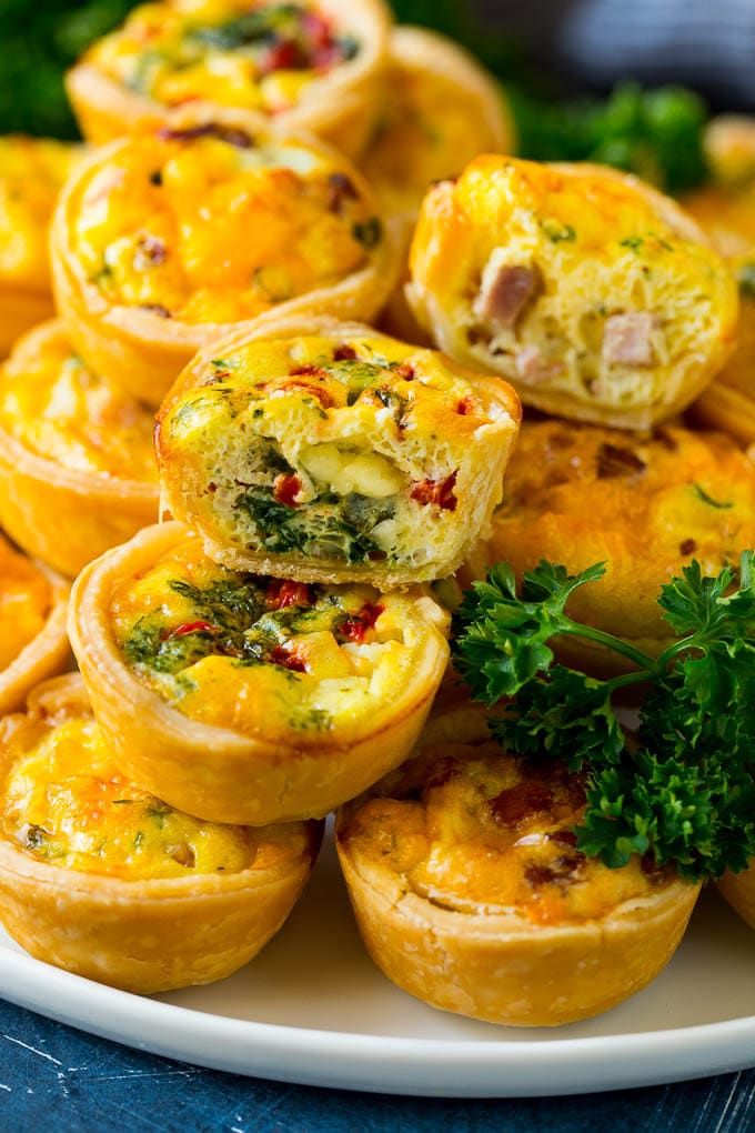 A serving platter of mini quiche with some cut in half.