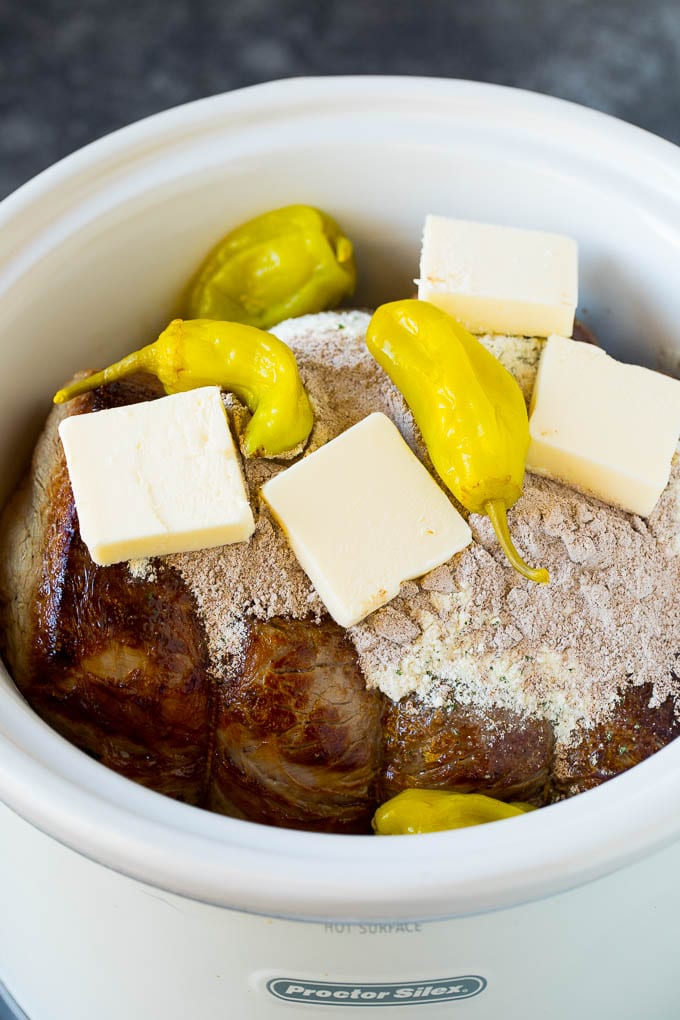 A pot roast topped with seasonings, pepperoncini peppers and butter.