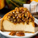 A slice of pecan pie cheesecake on a serving plate.