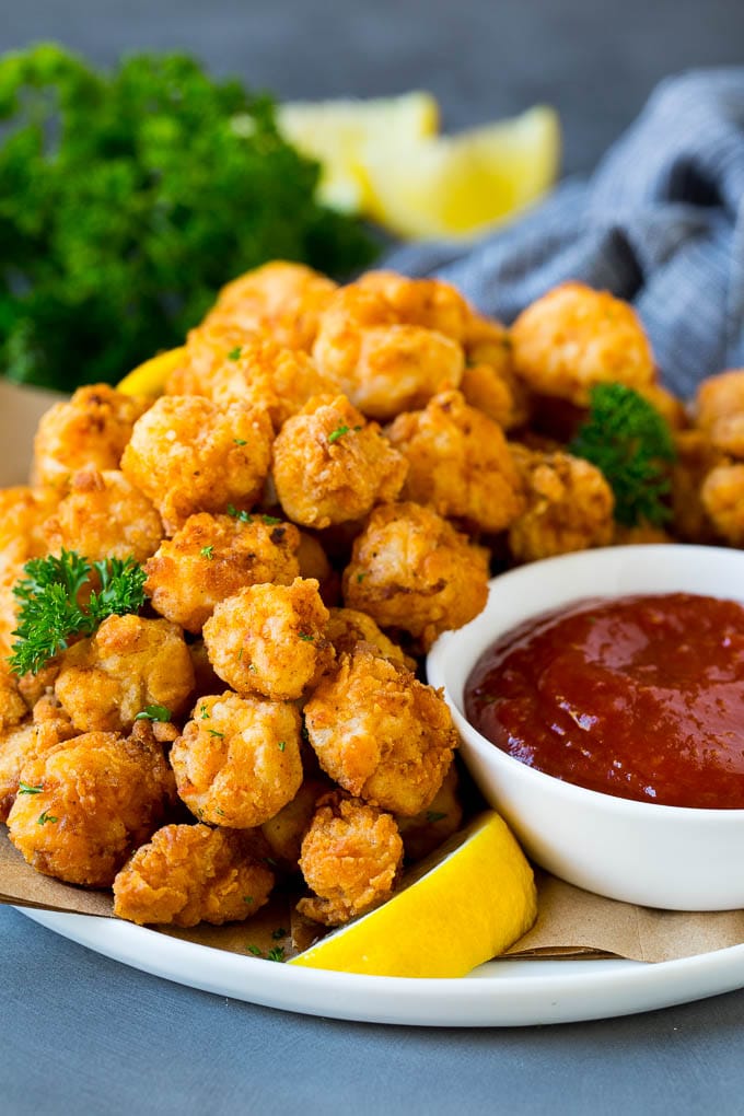 A plate of popcorn shrimp served with cocktail sauce.