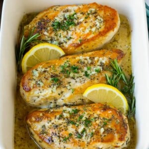 Baked rosemary chicken in a lemon sauce, garnished with fresh herbs.