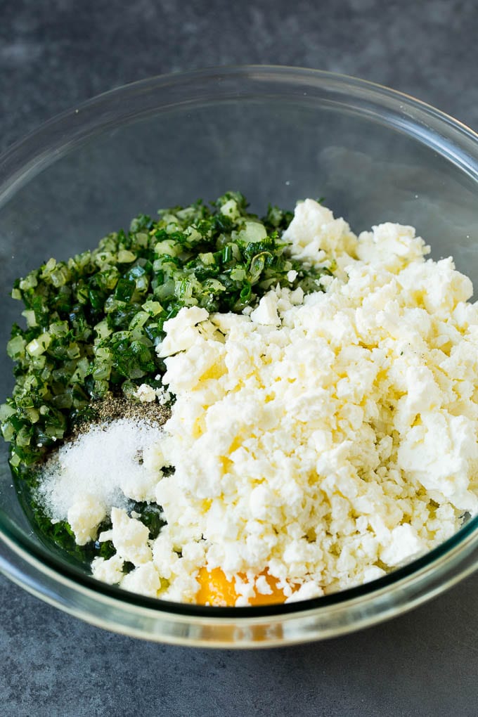 Spinach, onions, herbs and feta cheese in a bowl.