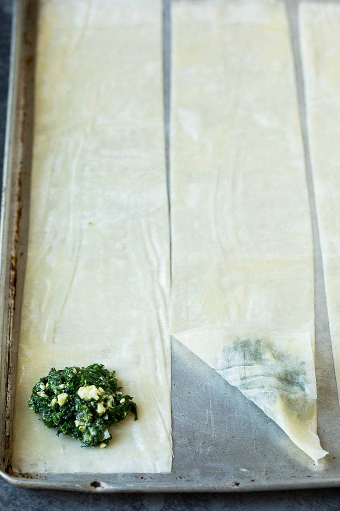 Strips of phyllo dough with spoonfuls of filling on top.