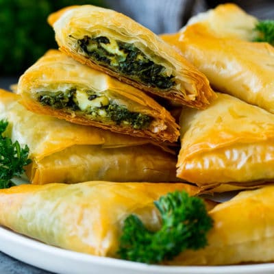 A plate of spanakopita with two cut in half.