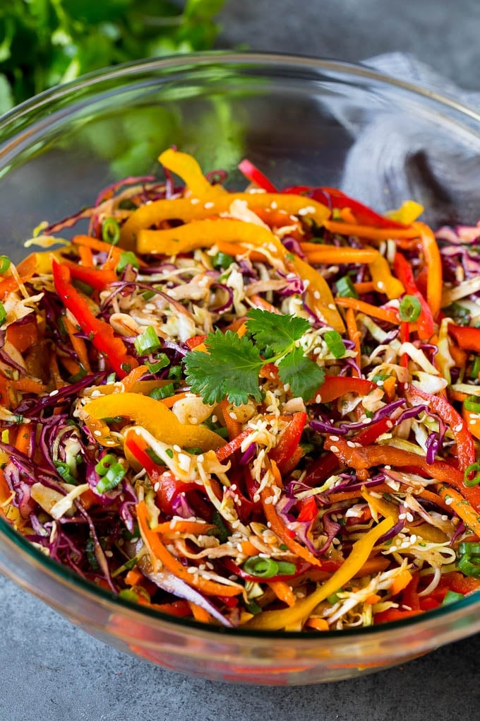 A bowl of Asian slaw garnished with sesame seeds and herbs.