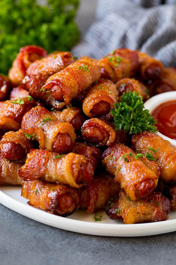 A plate of bacon wrapped smokies served with ketchup.