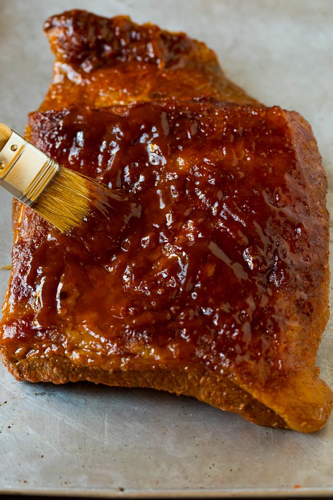 BBQ sauce being brushed over a piece of brisket.