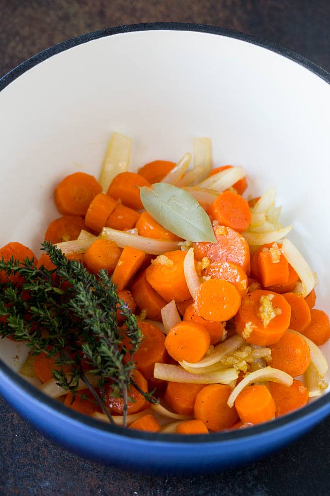 Carrots, onions and herbs in a pot.