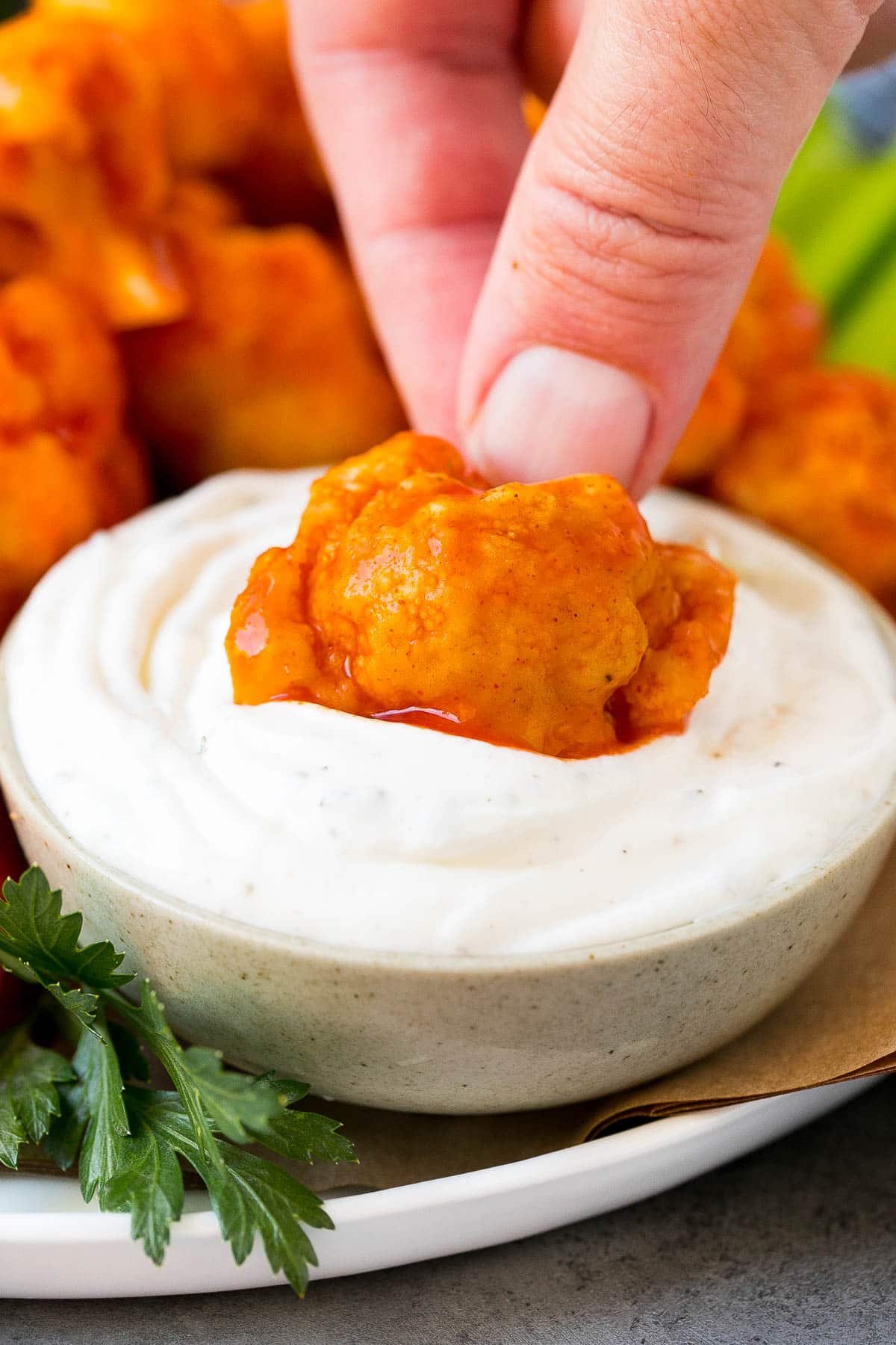 A hand putting a piece of buffalo cauliflower into ranch dip.