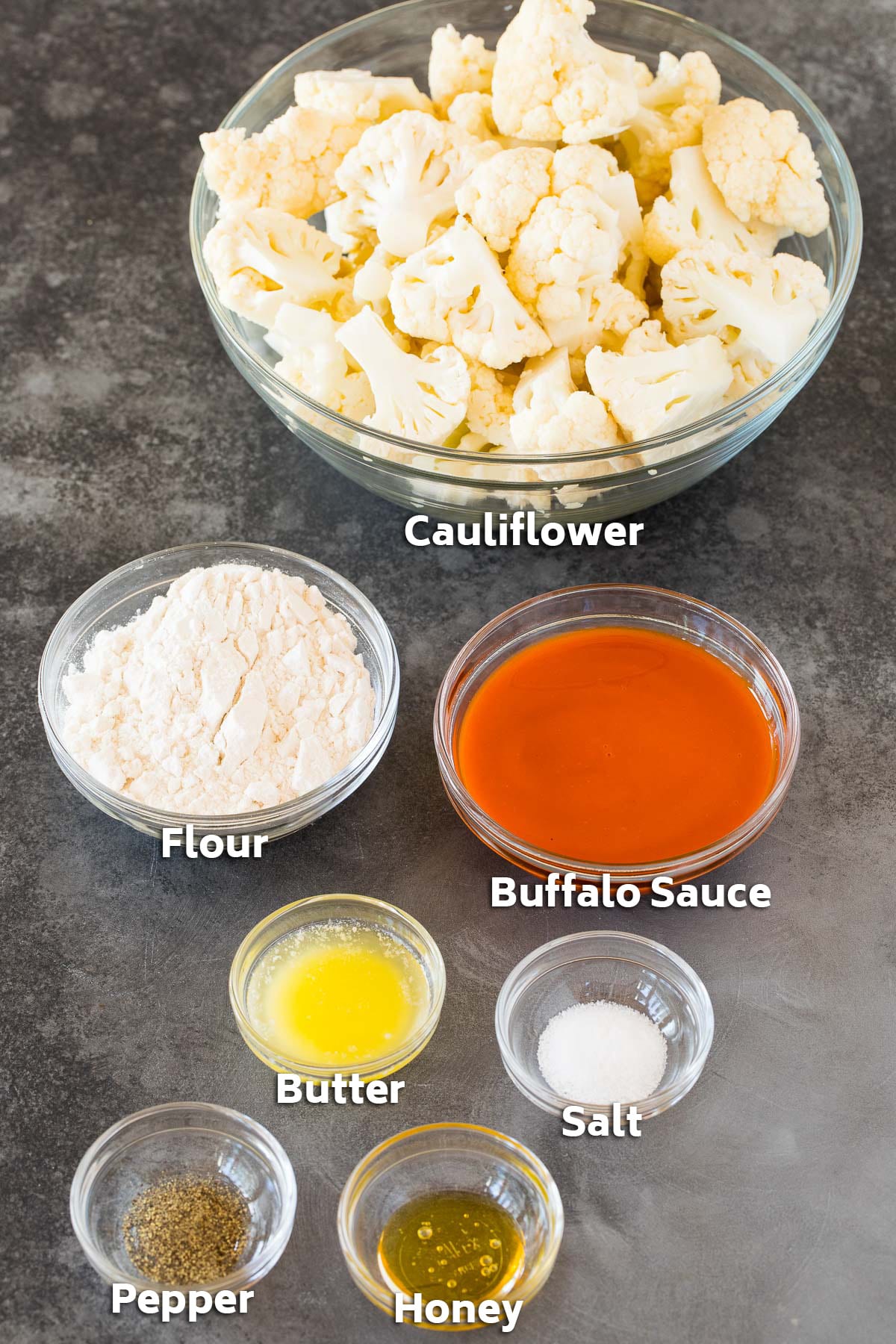 Bowls of ingredients including cauliflower, buffalo wing sauce and seasonings.