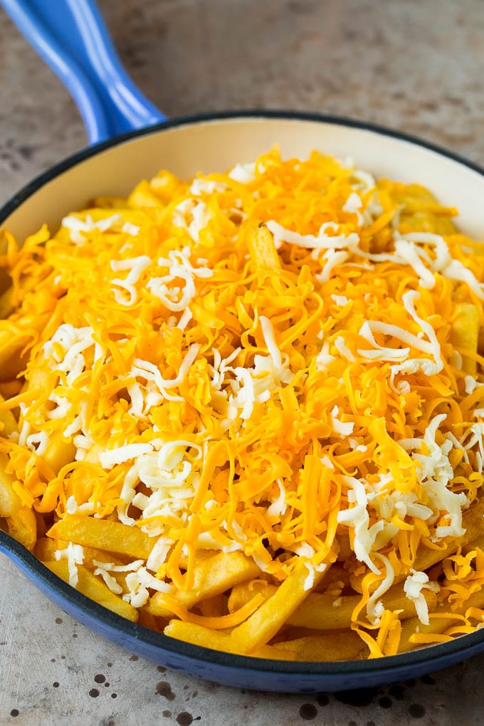 A skillet of fries topped with shredded cheese.