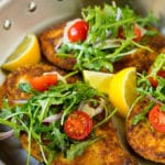 Chicken milanese topped with arugula salad in a skillet.