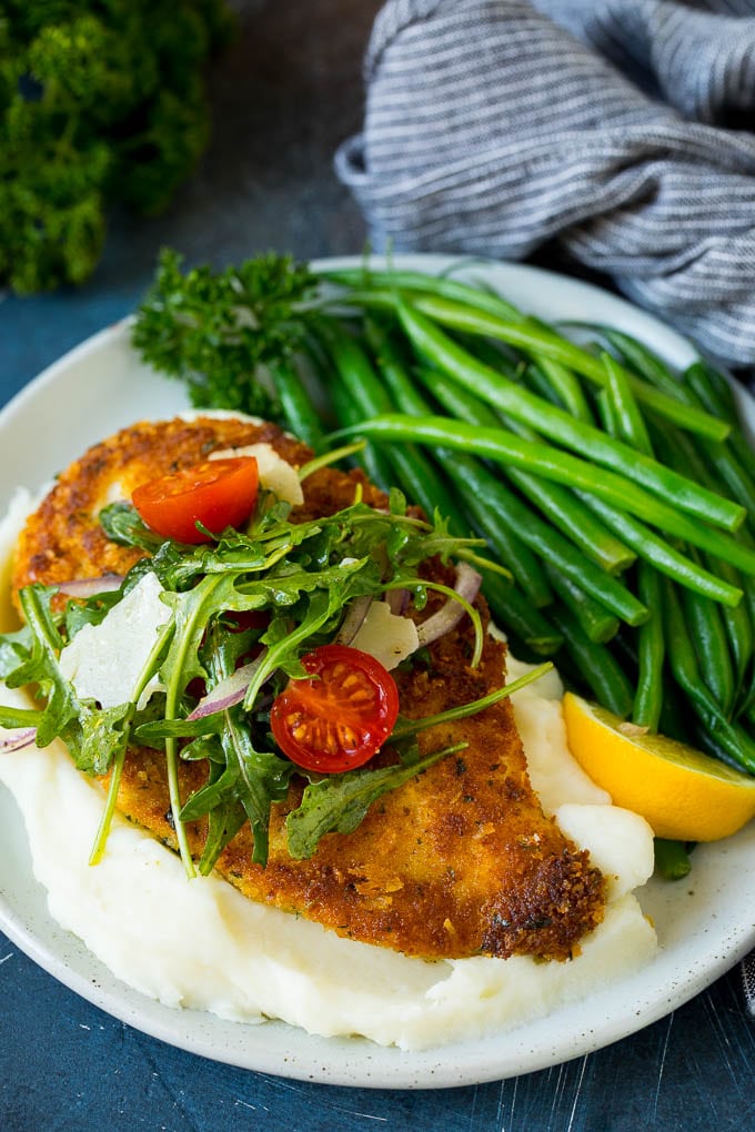 Chicken milanese served over mashed potatoes with a side of green beans.