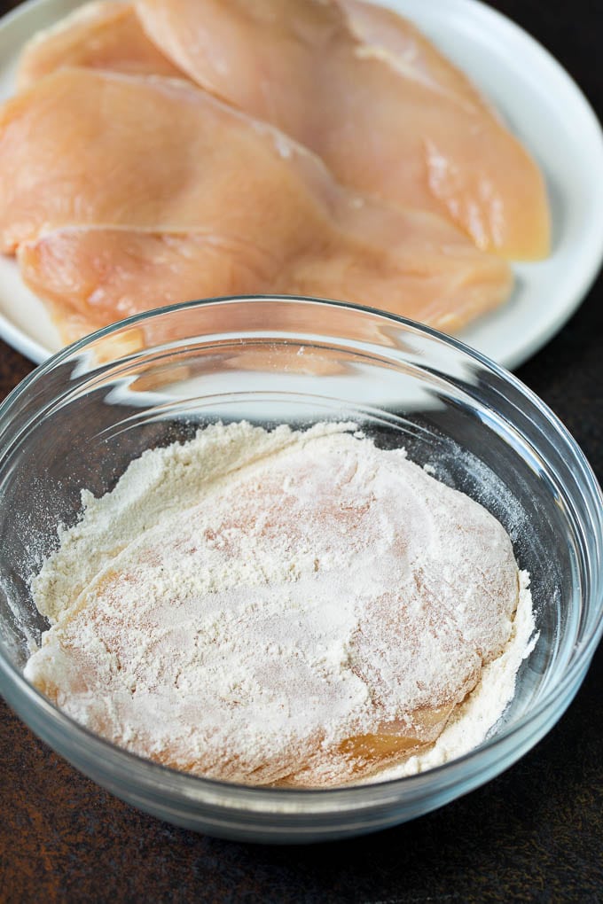 A chicken breast in a bowl of seasoned flour.