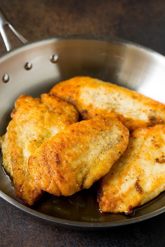 Seared chicken cutlets in a pan.